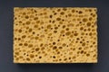 Close up view of cleaning sponge, mesh structure pattern on black surface. Yellow sponge close-up. Royalty Free Stock Photo
