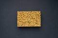 Close up view of cleaning sponge, mesh structure pattern on black surface. Yellow sponge close-up. Royalty Free Stock Photo