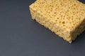 Close up view of cleaning sponge, mesh structure pattern on black surface. Yellow sponge close-up. Royalty Free Stock Photo