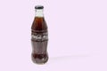 Close up view of Coca Cola in a glass bottle isolated on pink background.