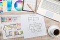 Close up view of color palette swatch and house building plans on office desk with laptop and cup of coffee for break Royalty Free Stock Photo