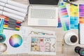 Close up view of color palette swatch and house building plans on office desk with laptop and cup of coffee for break Royalty Free Stock Photo