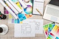 Close up view of color palette swatch and house building plans on office desk with laptop and cup of coffee for break Royalty Free Stock Photo