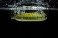 Close up view of colorful banana falling in water on black background.