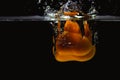 Close up view of colorful yellow pepper falling in water on black background. Royalty Free Stock Photo