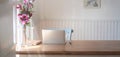 Close-up view of comfortable workplace with mock up laptop computer, office supplies and pink flower vase on wooden table Royalty Free Stock Photo