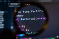 Close-up view of a computer screen displaying colorful programming code under a magnifying glass Royalty Free Stock Photo