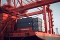 Close up view of container ship under loading. Freight vessel at the berth in cargo terminal. Port cranes loading