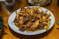 Close-Up View on Cooked Pork With Mushrooms. Southern Chinese Festivity Rural Food on Bowls and Plates at a Wooden Table