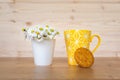 A cookie and a yellow cup of coffee and  a bunch of daisies in the background Royalty Free Stock Photo