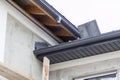 close-up view of corner of house with a gray roof and plums and filing of roof overhangs with soffits of house under construction