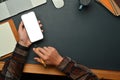 Close up view of creative man hands holding smart phone while sitting front of laptop at working desk Royalty Free Stock Photo