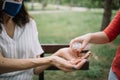 Close-up view of cropped people disinfecting hands with antiseptic spray outdoor