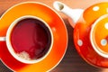 Close up view of cup with hot aromatic black tea and teapot with white polka dots on a wooden table. Tea time concept. Flat lay Royalty Free Stock Photo