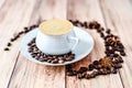 Close-up view of a cup of hot coffee on wooden rustic table with spilled coffee beans and anise. Royalty Free Stock Photo