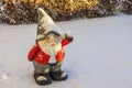 Close up view of cute figure of gnome standing in snow covered garden on sunny frosty winter day.