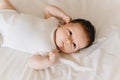 close up view of cute newborn baby in white bodysuit lying