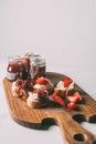 close up view of cutting board with fruit jam in jars and sandwiches with cream cheese and jam