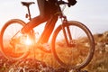Close-up View On A Cyclist. Biker Riding A Bike On The Way View From Below On A Background Of Sunrise.