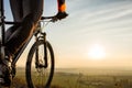 Close-up view on a cyclist. Biker riding a bike on the way view from below on a background of sunrise. Royalty Free Stock Photo