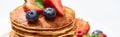 Close up view of delicious pancakes with honey, blueberries and strawberries, panoramic shot Royalty Free Stock Photo