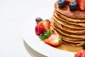 Close up view of delicious pancakes with honey, blueberries and strawberries on plate on white surface Royalty Free Stock Photo
