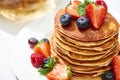 Close up view of delicious pancakes with honey, blueberries and strawberries on plate on white surface Royalty Free Stock Photo