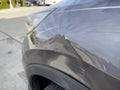 Close up view of a dent on the left side of a gray vehicle