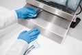 Close up view of dentist assistant`s hands in latex gloves holding packaged with vacuum packing machine dental instruments.