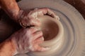 Close-up view on dirty man hands of potter creating with fingers and pressure an earthen jar pot of white clay on the potter`s Royalty Free Stock Photo