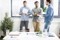 Close-up view of documents and business charts on desk and businessmen standing behind Royalty Free Stock Photo