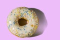 Close up view of donut sprinkled with multicolored glaze isolated on pink background.