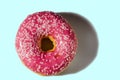 Close up view of donut sprinkled with white glaze isolated on blue background.