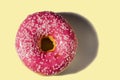 Close up view of donut sprinkled with white glaze isolated on yellow background. .