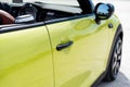 Close up view of door handle and side mirror of yellow Mini S Cooper sports cabriolet automobile with electric soft top Royalty Free Stock Photo