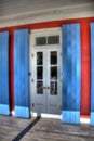 Close-up view of a door with a window with white shutters on a blue building Royalty Free Stock Photo