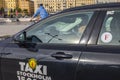 Close up view of driver in Taxi Stockholm vehicle and cyclist on old buildings background. Sweden.