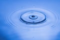 Close up view of Drops making circles on blue water surface isolated on background Royalty Free Stock Photo