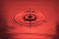 Close up view of Drops making circles on blue water surface isolated on red background Royalty Free Stock Photo