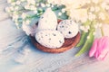 Close up view of easter eggs in a nest. Spring flowers and feathers over blue rustic wood background. Royalty Free Stock Photo