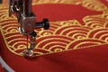 Embroidery of traditional shell pattern framing pig outline with gold on red fabric by modern embroidery machine