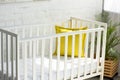 close up view of empty baby crib with yellow pillow