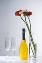 close up view of empty glasses, bottle of champagne and bouquet of gerbera flowers Royalty Free Stock Photo