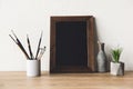 close up view of empty photo frame, vase and paintbrushes