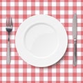 Close up view of empty white dish with knife and fork placed on classic checkered red tablecloth seamless background. View from