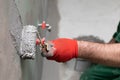 A close-up view of an experienced construction worker applying damp insulation using a paint roller on a wall