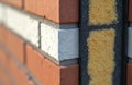 Close-up view of external wall insulation systems. Brickwork structure detail. Red brick, white brick, yellow insulation panels. Royalty Free Stock Photo
