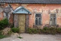 Close-up view of the facade of an old abandoned house. Wooden entrance door, windows, shabby plastered brick walls Royalty Free Stock Photo