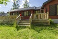 Close up view of facade of typical wooden swedish house with wooden patio.Red walls and contrast black windows. Sweden.