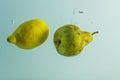 Close up view of falling lemon and pear into water. Healthy food concept.